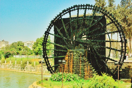 a large water wheel covered in algae and moss.