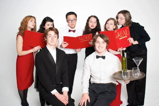 student cast members dressed in red and white pose for a photo.