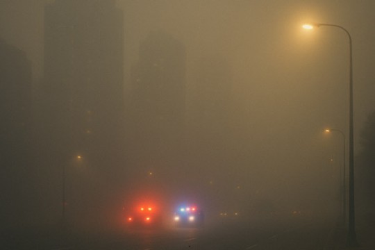 a photo of car lights through dark smog.