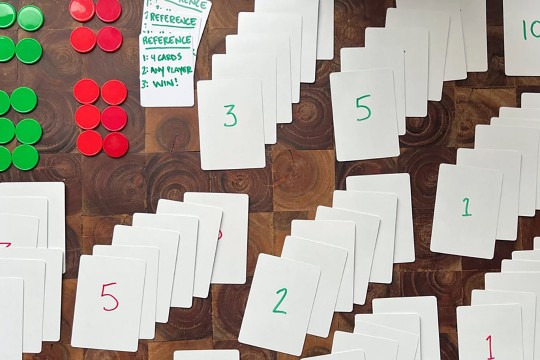 a game of homemade cards is laid out on a table with green and red chips.
