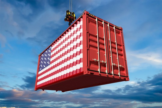 a shipping container painted to look like the american flag is hanging by a crane.