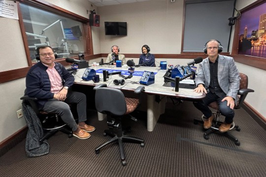 four people sit next to each other at a table with microphones.