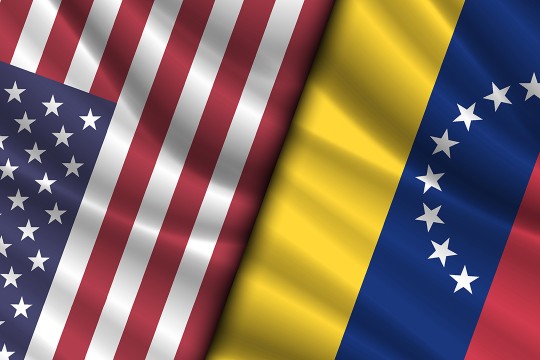 An edited image showing the United States of America and Venezuelan flags side by side. The US flag is on the left and the Venezuelan flag is on the right. Both flags are oriented vertically and only part of each flag is showing.