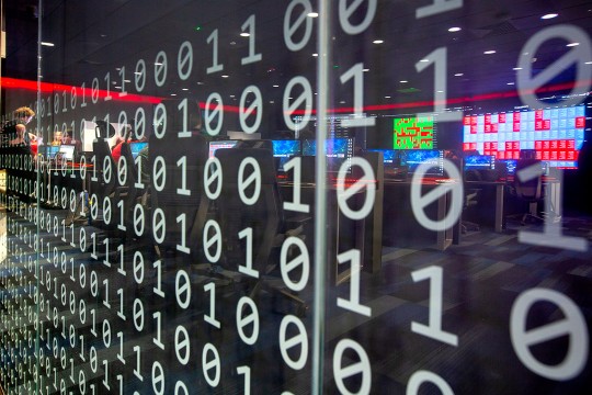 'a transparent wall reflecting computers is covered in decals of ones and zeroes.'