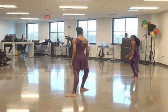 'Woman in dance outfit stands performs in a large room.'