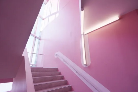 pink stairwell with geometric walls and tall window casting soft light