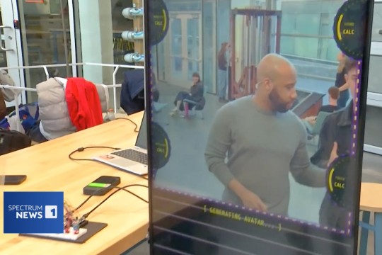 a man is shown on a large vertical computer screen being prepped for an AI makeover.