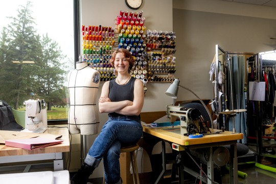 Emily Ohl works at a table with a sewing machine.