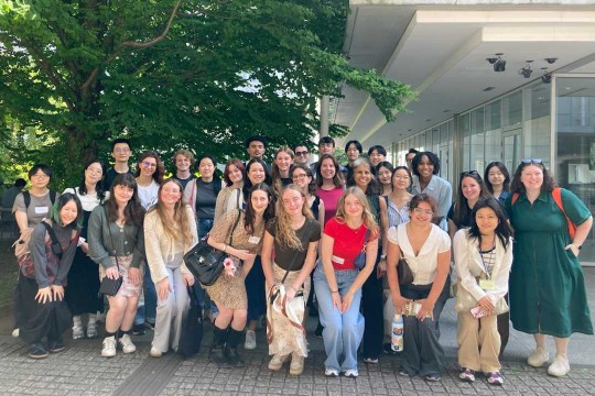 A group of students posing outside in front of a building with trees in the background