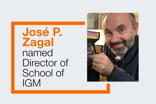 Jose Zagal smiling and pressing a button on a mini arcade cabinet