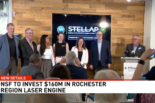 a group of people stand in front of a wooden background with a T V that says 'STELLAR' 