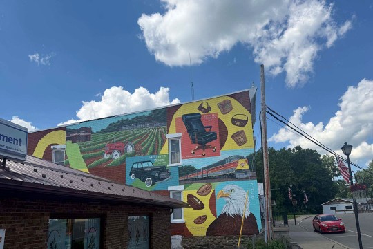 Colorful mural depicts local history and landmarks on a downtown brick building.