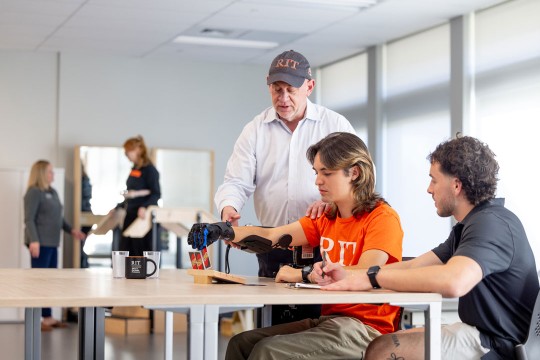 'Joshua Luciano, right, shows new ways to apply design interventions that support movement and independence. Stephen Van Lew, left, assistant professor, demonstrates how to use a rehabilitation glove. '