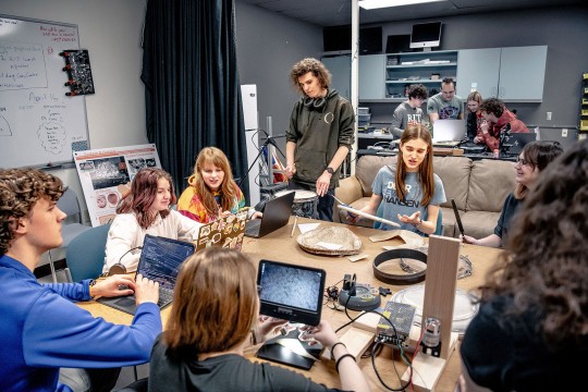 a group of students in an imaging lab work together with laptops and tools.