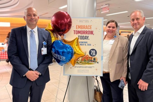 three people stand next to a sign with balloons celebrating the anniversary of R G H