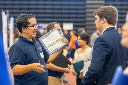'two people talk at the career fair'