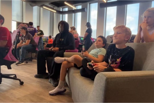 kids sit on a sofa in an office environment playing video games