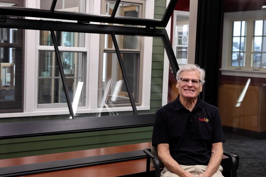 Tim Forster smiling while sitting in front of a large FoldUp window