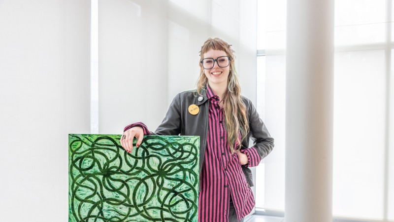 A young woman standing in front of a green hued canvas