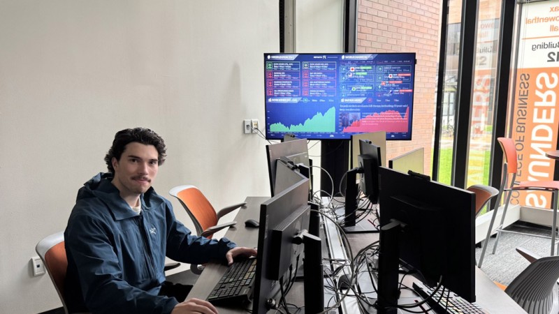 Student sitting in front of computers smiling