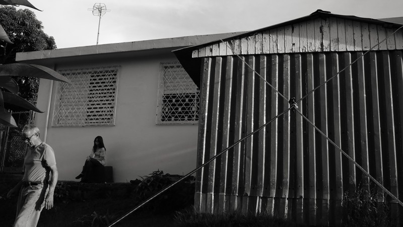 A couple people walk and stand outside a house.