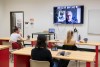 professor on a TV screen in front of classroom with students.