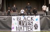 Students dancing on outdoor stage, BLM flag in foreground.