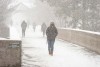 Students walk in snowfall down pathway