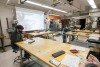 3 students work in mechanical engineering lab with tools and wood tables