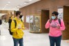 two NTID students sign in hallway wearing masks