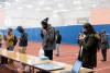 students stand in field house and perform Covid tests on themselves
