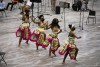 four students wearing traditional African clothing dancing.