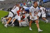 lacrosse players in a celebratory pile on the ground.