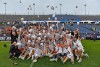 men's lacrosse team gathers for photo on field throwing hats into the air.