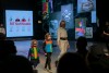 model and two childen walk down a stage.