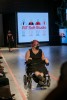 model in a wheelchair comes down a stage.