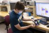 Students tinker with robots at their work stations.
<br><p>Photo by A. Sue Weisler</p>