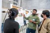 student giving poster presentation to two people.