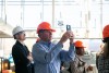 person wearing a hard hat taking a photo with a phone.