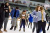 college students holding hands while ice skating.