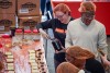 volunteer scooping jelly out of a jar at a table lined with peanut butter and jelly sandwiches.