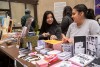 two college students talking at a craft table for small magazines.