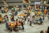 wide view of several round tables with college students decorating their mortarboards.