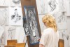 high school art student looking at her self-portrait done in charcoal.