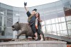 two students sit on a tiger statue in front of the R I T building called The Shed.