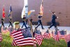 american flags in the foreground with army R O T C members marching behind