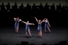 Four dancers perform with orchestra silhouettes behind