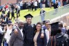 A graduate in cap and gown poses for a picture with family members.