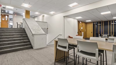 a common area with a set of stairs going up and another going down, with a table and chairs on the main level.