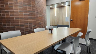 a meeting room with a table and six chairs, and a brick wall.